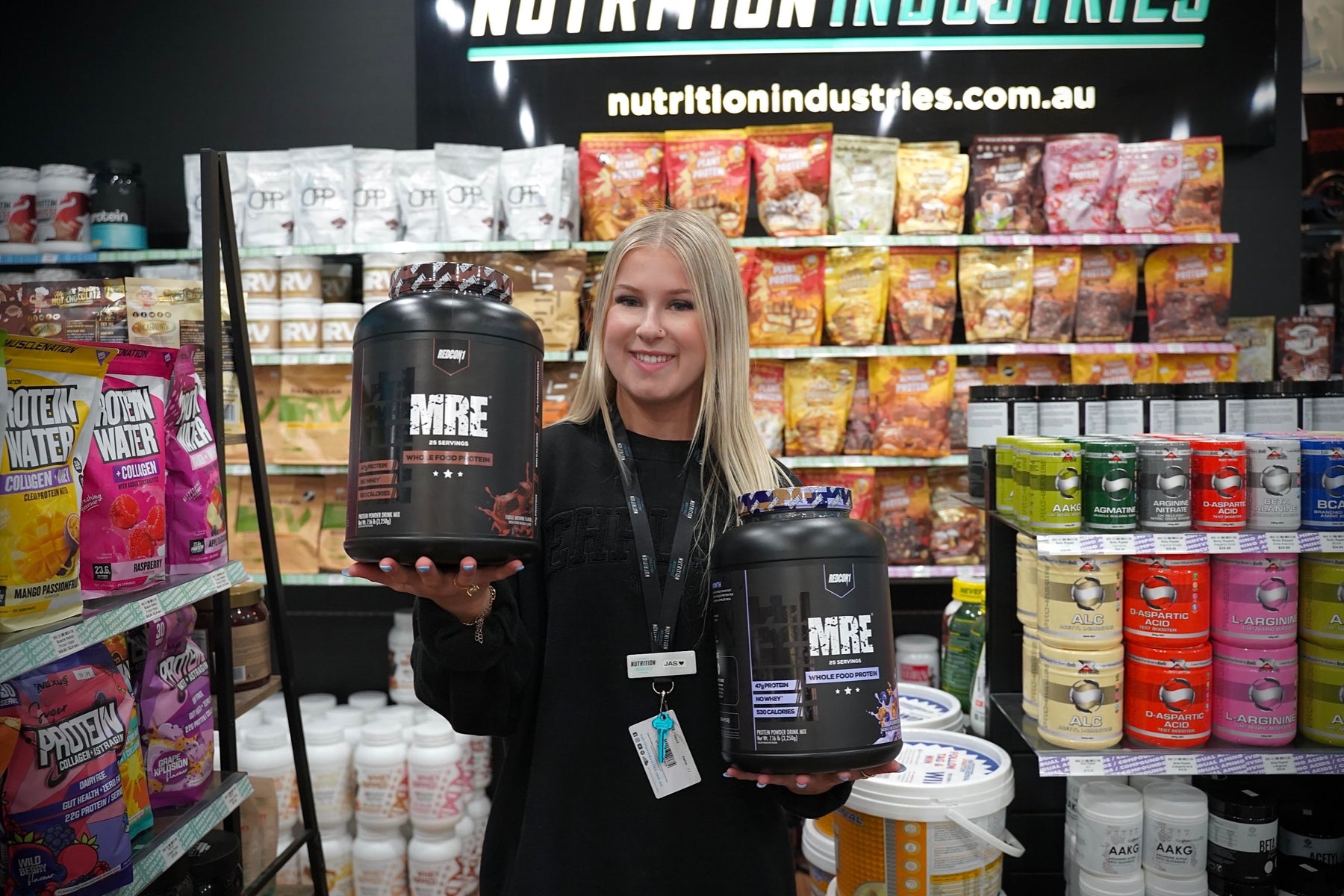 Jas holding MRE supplement tubs in Nutrition Industries store