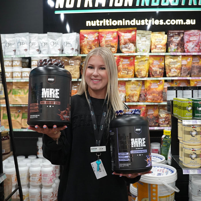 Jas holding MRE supplement tubs in Nutrition Industries store